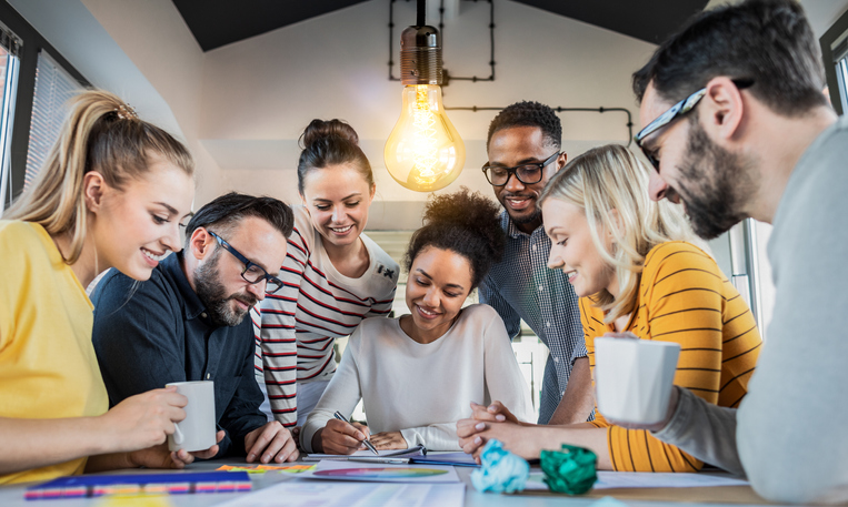 Jovens empresários estão discutindo juntos um novo projeto de marketing. Uma lâmpada incandescente como uma nova ideia.