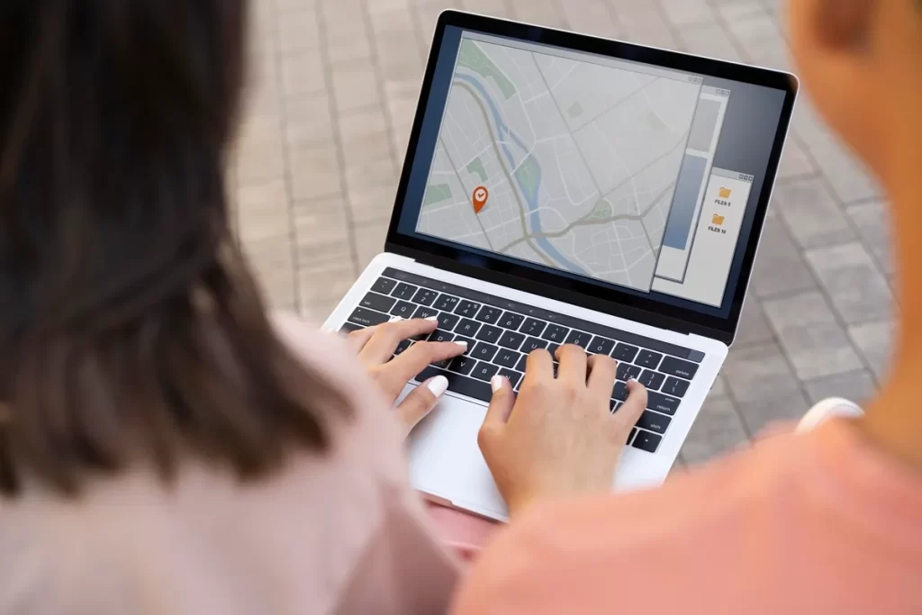 Pessoa utilizando um laptop com mapa digital na tela, destacando um marcador de localização.