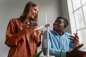 Duas pessoas discutindo um projeto de energia eólica, com um modelo de turbina eólica na mesa, representando colaboração em soluções sustentáveis.